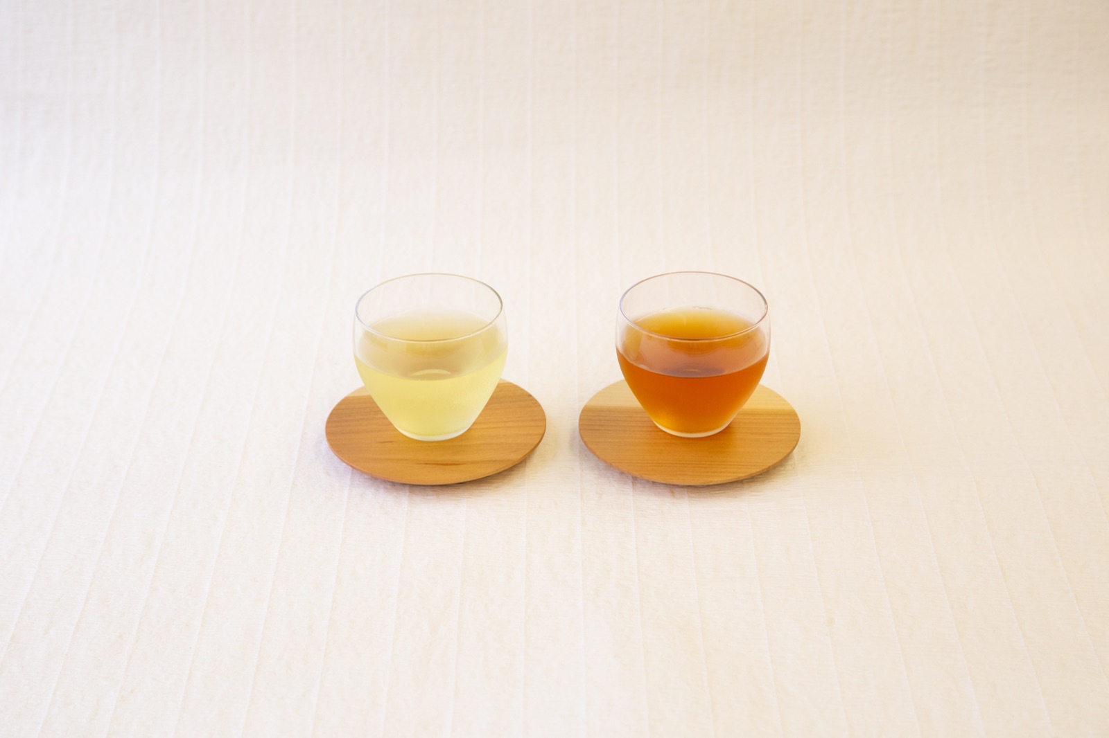 木のコースターに並べた二つのお茶の色合い